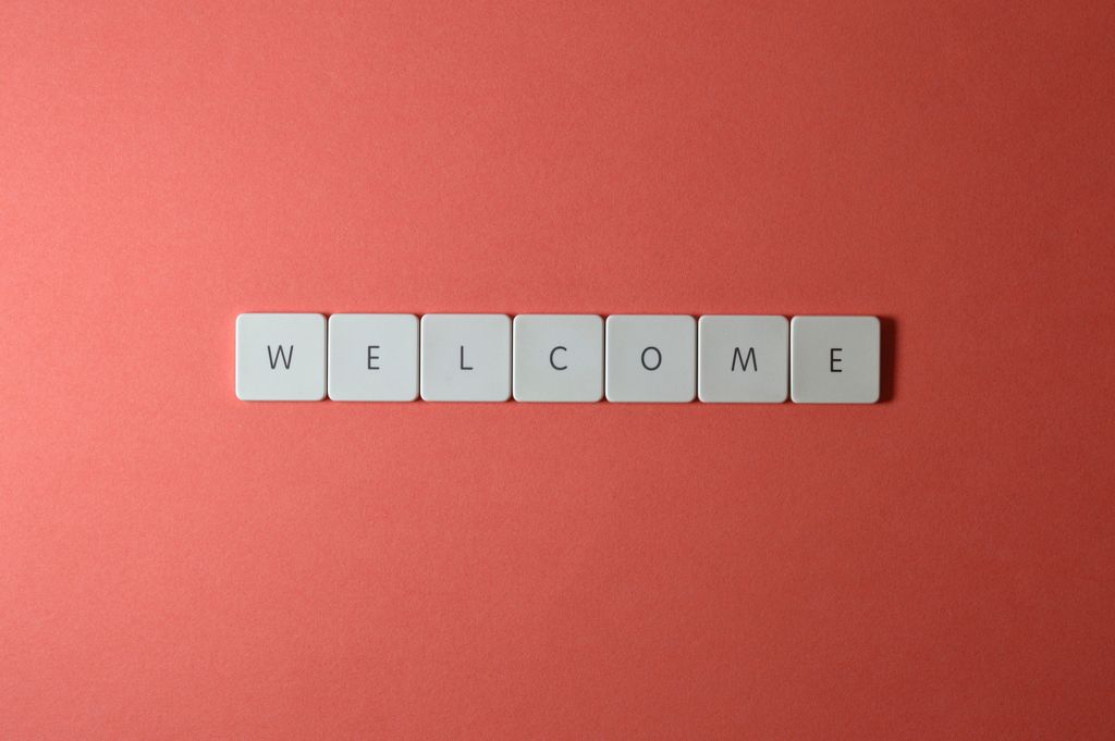 Flat lay of white tiles spelling 'WELCOME' on a red background