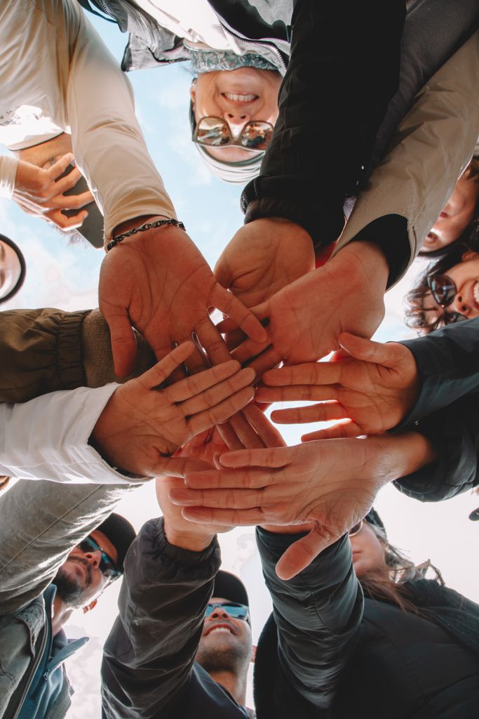 Overhead view of diverse group uniting hands in São Paulo, symbolizing teamwork and community.