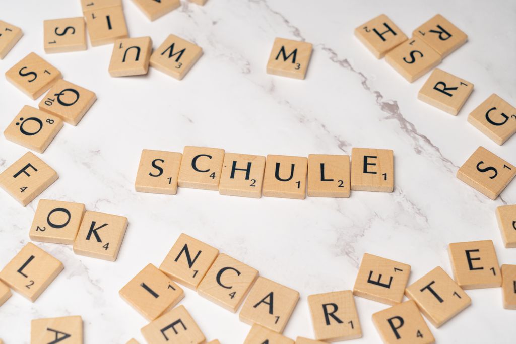 Scrabble letter tiles spelling 'Schule' on a marble surface, ideal for language learning concepts.